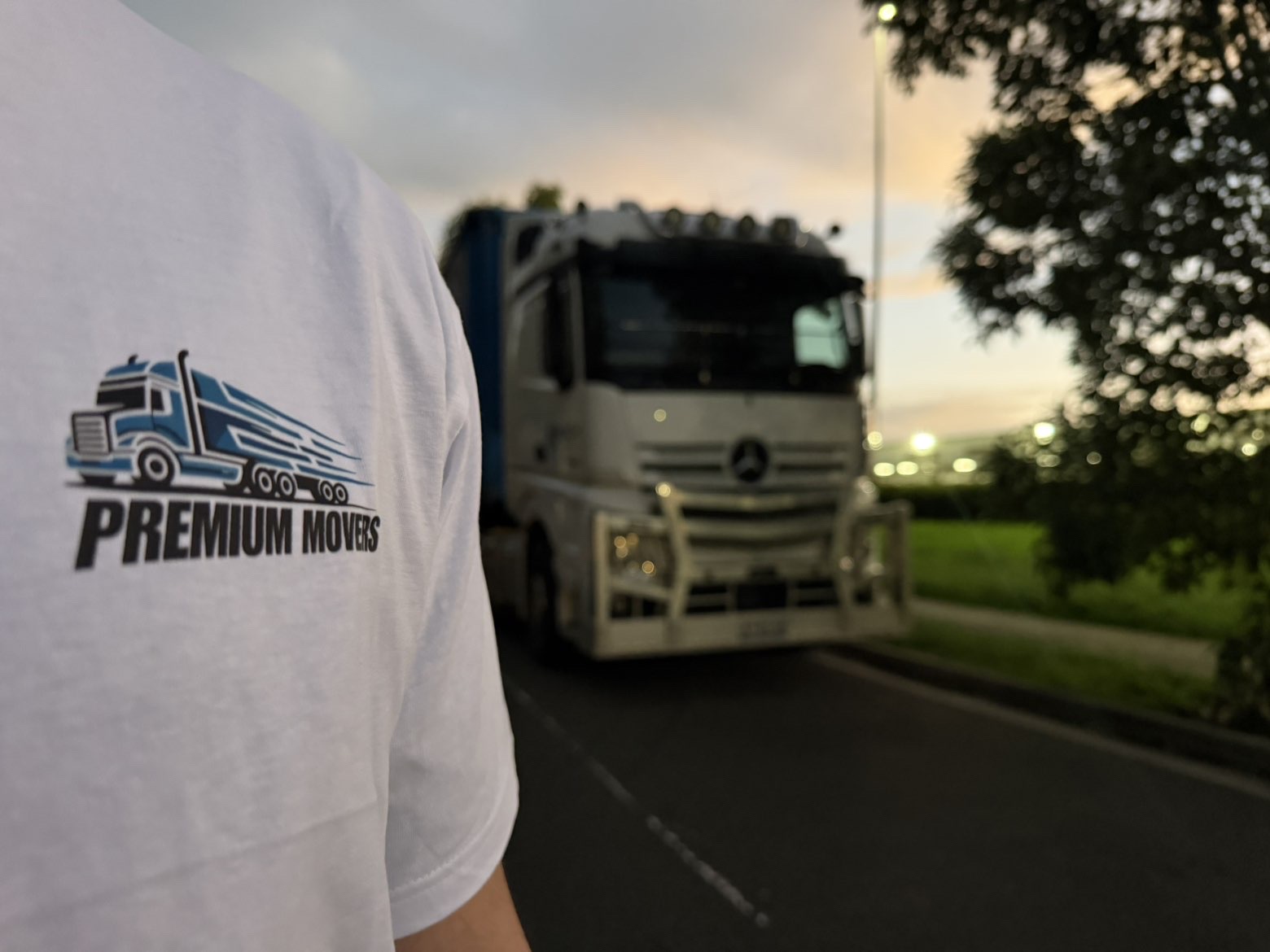 Premium Movers branded work shirt beside a moving truck